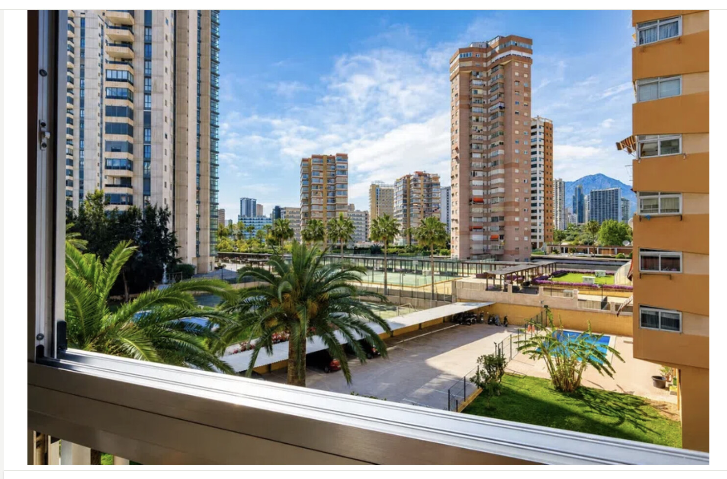 Vistas desde la terraza a piscina, pistas deportivas y skyline de Benidorm